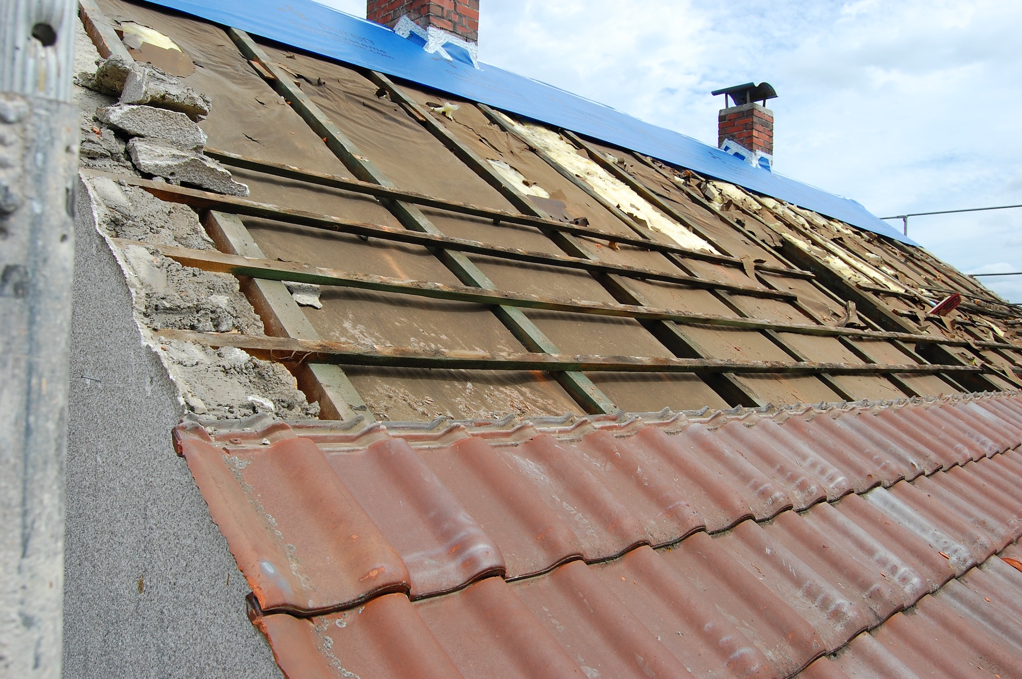 Work on a roof. Partly removed roof tiles and still old insulation.